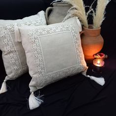 two decorative pillows with tassels next to a lit candle