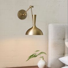 a white vase sitting on top of a wooden table next to a wall mounted lamp