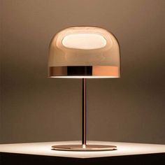 a table lamp that is on top of a white surface with light coming from it