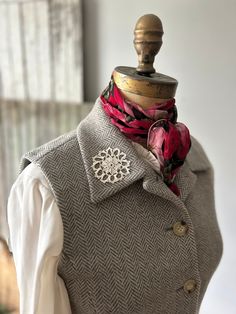 a mannequin wearing a gray vest with pink and red flowers on the lapel