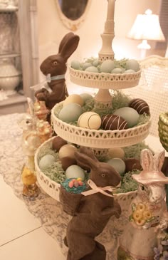 three tiered trays filled with chocolate eggs and bunny figurines on a table