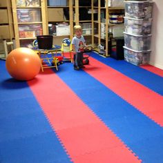 a young boy standing in the middle of a room with an exercise mat on the floor