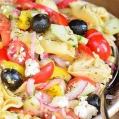 a bowl full of pasta salad with olives, tomatoes, and other toppings