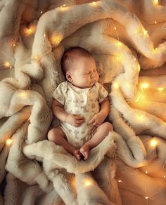 a baby is sleeping on a blanket with lights around it