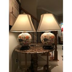 two lamps sitting on top of a marble table next to a stair case in a house