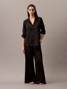 Elevated and sensual, this relaxed button-down shirt is crafted from silky satin with a luxurious feel. Designed with a collar and a v-neckline, button barrel cuffs and an elegant drape. Detailed with clean finish hems for a simple, timeless look.  Material: 100% Polyester. Satin Button Down Shirt, Satin Pyjama, Top Calvin Klein, Swimwear Suits, Party Kleidung, Jeans Bag, Satin Pajamas, Business Outfit, Pajama Top