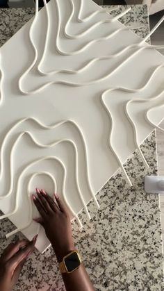 a woman is working on an art project with white paper and plastic glue, which looks like wavy lines