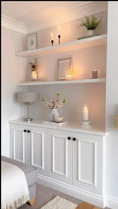 a living room with white shelves and candles