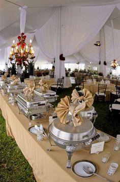 a table with many plates and silverware on it in a tented area at an event