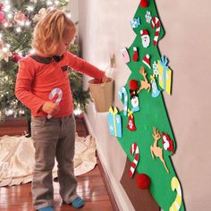 a little boy standing in front of a christmas tree with decorations on the bottom half