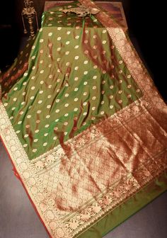 Embrace vibrant sophistication with the Green and Red Dual Tone Katan Silk Saree, adorned with intricate zari buttas and a striking red contrast. Crafted from luxurious Katan silk, this saree offers a sumptuous texture and a fluid drape that enhances its elegant appeal. The saree's captivating dual-tone effect seamlessly blends rich green and vibrant red hues, creating a dynamic and visually stunning contrast. The intricate zari buttas, meticulously woven throughout the fabric, add a touch of timeless opulence, creating a beautiful interplay of light and texture. Ideal for weddings, festive occasions, or any special celebration, this saree effortlessly merges traditional Banarasi craftsmanship with modern style, ensuring you make a memorable and stylish statement SILK MARK CERTIFIED This s Green Sari, Katan Silk Saree, Katan Silk, Sari Fabric, Rich Green, Green And Red, Blouse Fabric, Saree Wedding, Vibrant Red