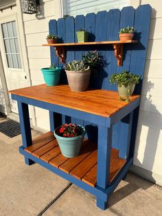 two potted plants sit on top of a wooden table with shelves above it and below them