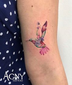 a hummingbird tattoo on the right arm and shoulder, with pink flowers around it