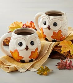 two coffee mugs decorated with owls and leaves