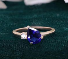 a tan gold ring with a pear shaped blue sapphire and two white diamonds on it