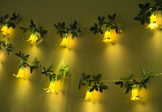 some lights are hanging on the wall with plants growing out of them and green leaves