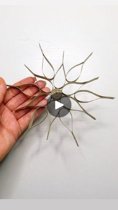 a hand holding a piece of metal wire with a hole in it