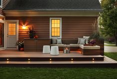 an outdoor living area with lights on the steps and couches in front of it