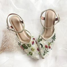 a pair of white shoes with flowers on them sitting on top of a white cloth