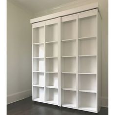 an empty white bookcase in the corner of a room