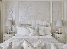 a bed with white sheets and pillows in a bedroom next to two lamps on either side of the bed