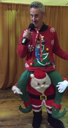 a man in an ugly santa suit holding a microphone