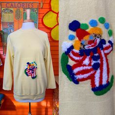 two sweaters on display next to each other in front of a wall with pictures