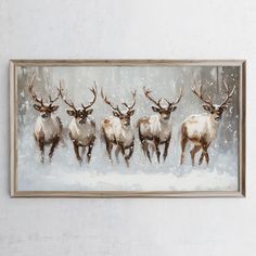 a group of deer running through the snow in front of a white wall with a wooden frame