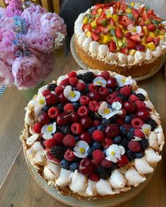 there are two cakes on the table with flowers and fruit toppings in them,