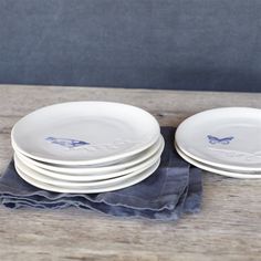 four white plates stacked on top of each other in front of a blue cloth napkin