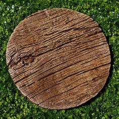 a round wooden object laying on top of some green grass in the middle of a field