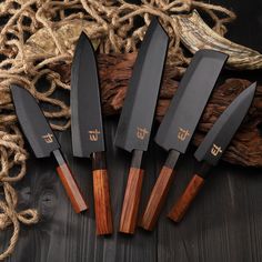 five knives sitting on top of a wooden table next to rope and burlock