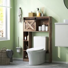 a bathroom with green walls and a toilet next to a cabinet in the middle of the floor