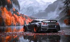 a black sports car parked on the side of a lake in front of mountains and trees