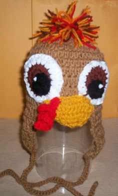 a crocheted hat with an orange nose and red hair on top of a glass cup