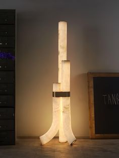 a tall white sculpture sitting on top of a hard wood floor next to a wall