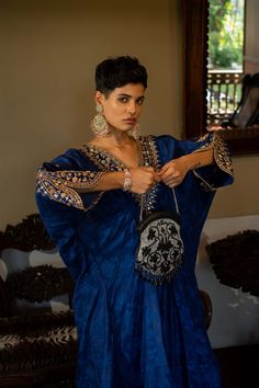 Editor's Note Featuring a deep blue self-woven kaftan with hand embroidery on yoke and cuffs. This elegant piece comes embellished with careful antique embroidery detailing. Color: Blue Fabric: Russian jacquard Component: Kaftan Fit: Relaxed Occasion: Resort and evening wear Care: Dry Clean Only About the Designer Paulmi & Harsh is a luxury prêt label inspired by beautiful botanicals. Paulmi & Harsh design strong, feminine silhouettes with prints and delicate detailing, fusing 1950’s fashion wit