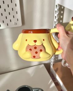 a person holding a yellow dog mug in their hand