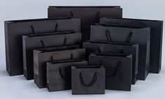 black paper bags with handles are stacked on top of each other in different sizes and shapes