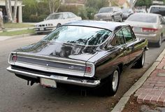 an old car is parked on the side of the road in front of other cars