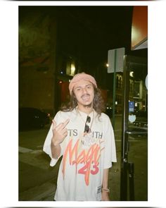 a man with long hair wearing a pink bandana standing in front of a bus