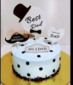 a white cake with black polka dots and a top hat on it is sitting on a table