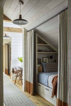 an attic bedroom with white walls and wood flooring, built into the side of a house