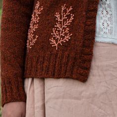 a close up of a person wearing a sweater with flowers on the front and side