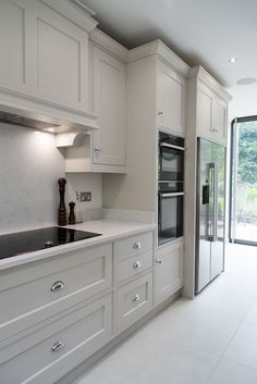 a kitchen with white cupboards and an oven in the center, next to a sliding glass door