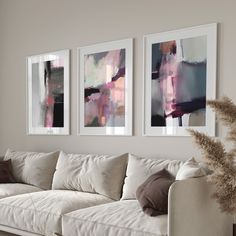 three paintings hang on the wall above a couch in a living room with white furniture