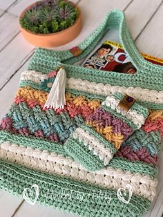 a crocheted purse sitting on top of a wooden table next to a potted plant