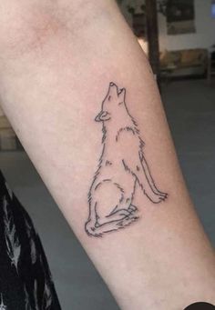 a small tattoo on the arm of a person with a dog sitting in front of it