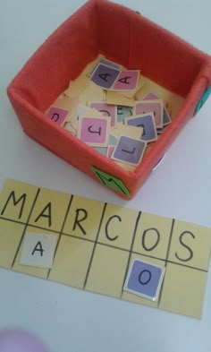 a box filled with cut out letters sitting on top of a table next to a scrabble