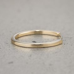 a thin yellow gold ring on a gray surface